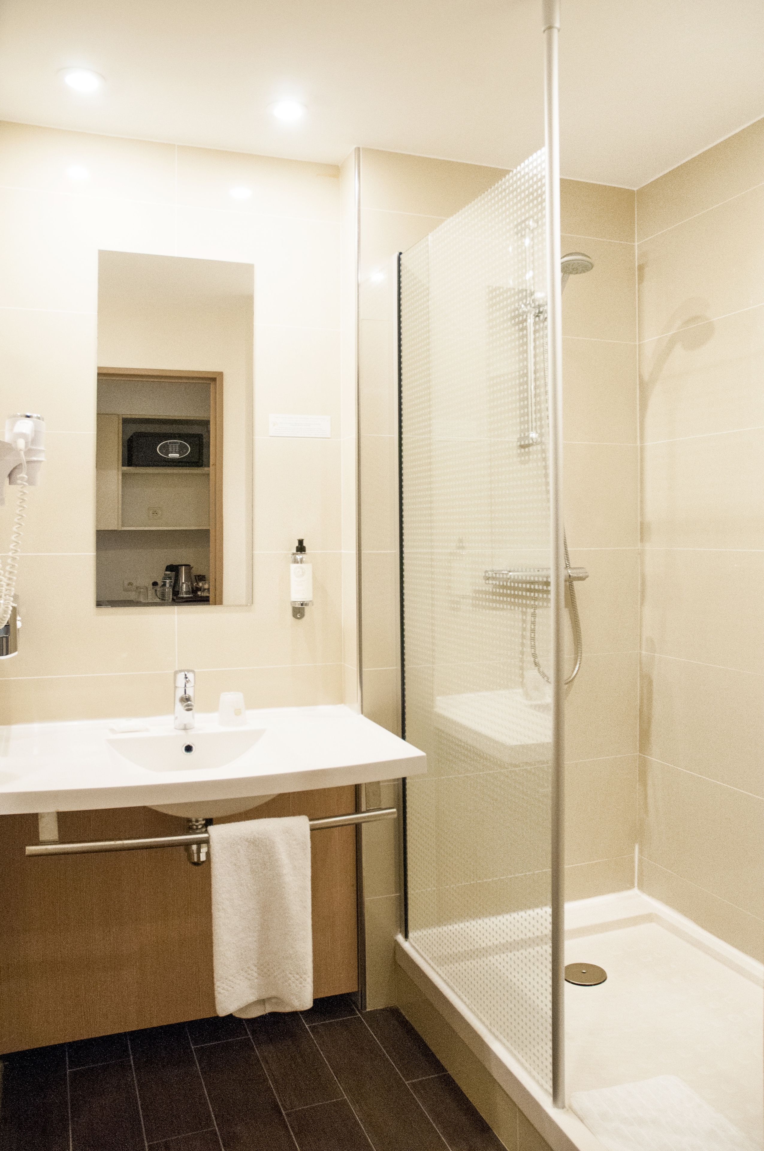 A modern bathroom with a glass-enclosed shower, a white sink, and a towel rack.