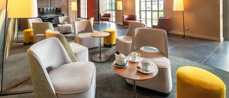 A modern hotel lobby with comfortable seating, a piano, and large windows.