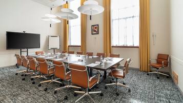A conference room with a large table, chairs, a TV, and a whiteboard.