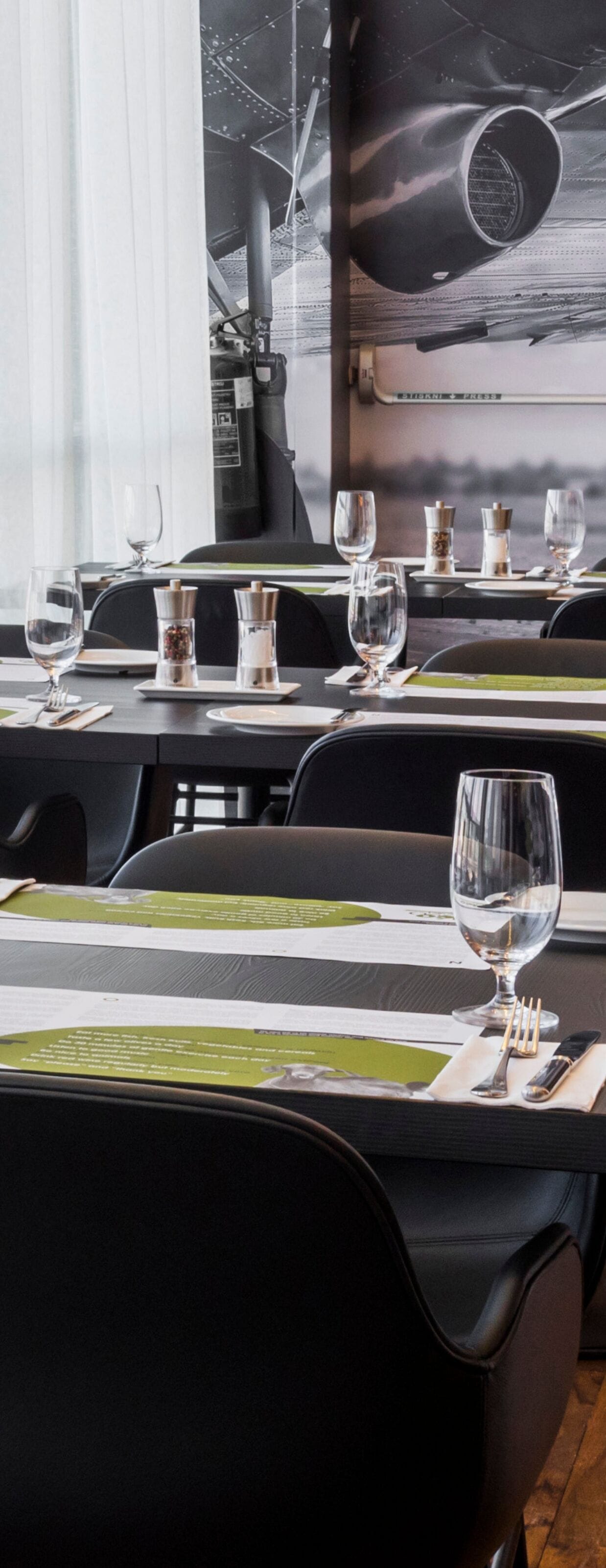Un restaurante con mesas dispuestas para comer, mostrando un menú y copas de vino.