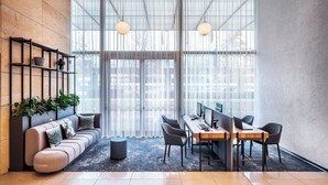 Un espace de bureau moderne avec un long canapé incurvé, un mur d’accent en bois et une grande fenêtre agrémentée de rideaux légers.