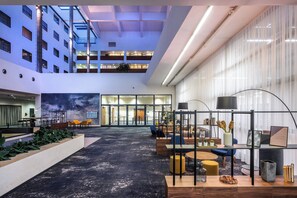 Un amplio atrio interior con techo alto, varias zonas de estar y un jardín central.