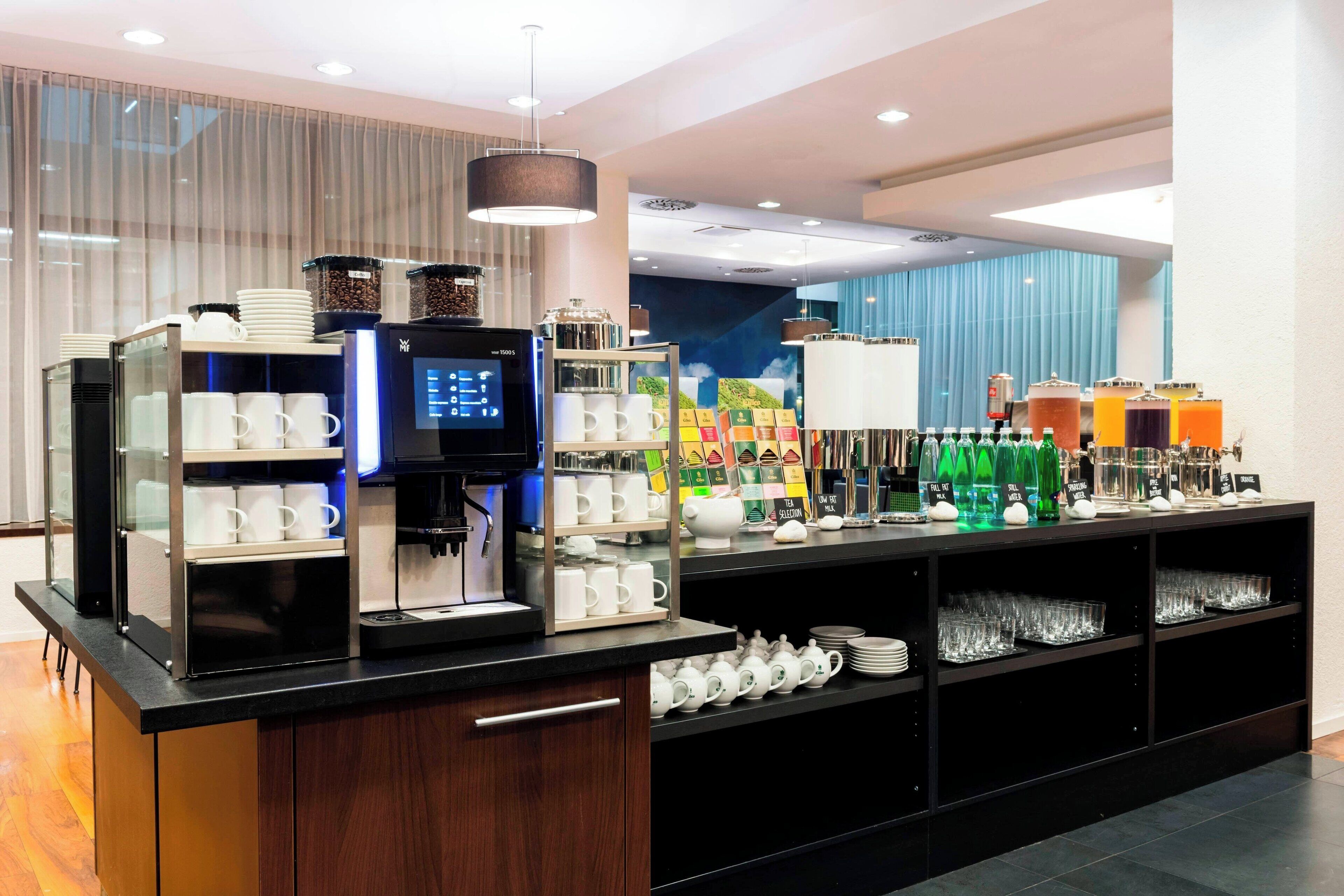 Un bar à petit-déjeuner moderne, équipé de machines à café, de distributeurs de thé et proposant une grande variété de boissons.