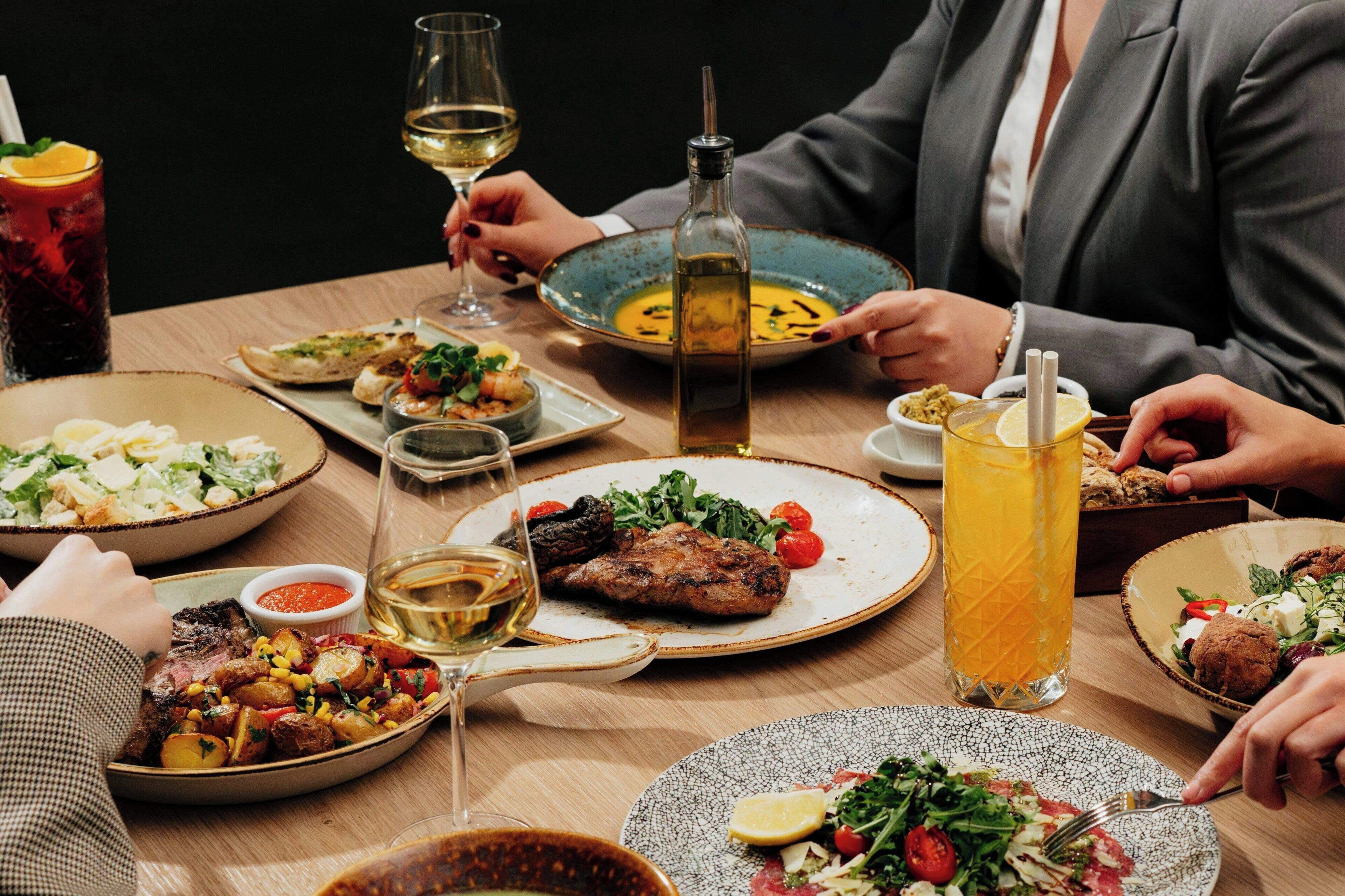 Uma mesa de jantar com diversos pratos, bebidas e uma garrafa de azeite.
