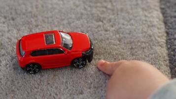 Un coche de juguete rojo sobre una alfombra.