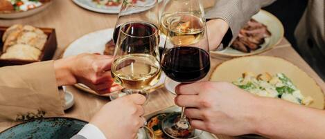 A group of people toasting with wine glasses at a dining table with various dishes.