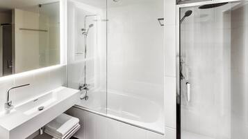 Ein modernes Badezimmer mit einer gläsernen Dusche, einem weißen Waschbecken und einem großen Spiegel.