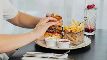 A plate with a burger, fries, and two small containers of condiments.