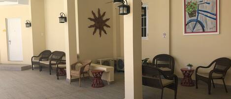 A spacious indoor area with wicker chairs and tables, a sun decoration, and a bicycle painting on the wall.