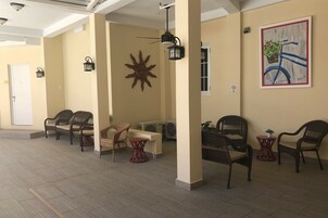 A spacious indoor area with wicker chairs and tables, a sun decoration, and a bicycle painting on the wall.