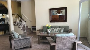A living room with wicker furniture, a sofa, a coffee table, and a staircase with a railing. - Hotel Villa del Sol (Carolina)
