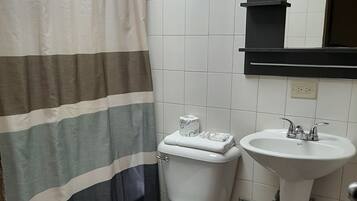 A bathroom with a striped shower curtain, a toilet, a sink, and a mirror above the sink.