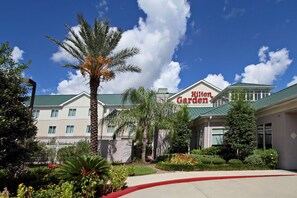 Ein Hilton Garden Hotel mit Gründach, umgeben von Palmen und gepflegten Gärten.