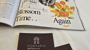 A magazine open to a page with the text "Blossom Time... Again" and two business cards for Portapia Hotel. - Hotel Porta Pia (Rome)
