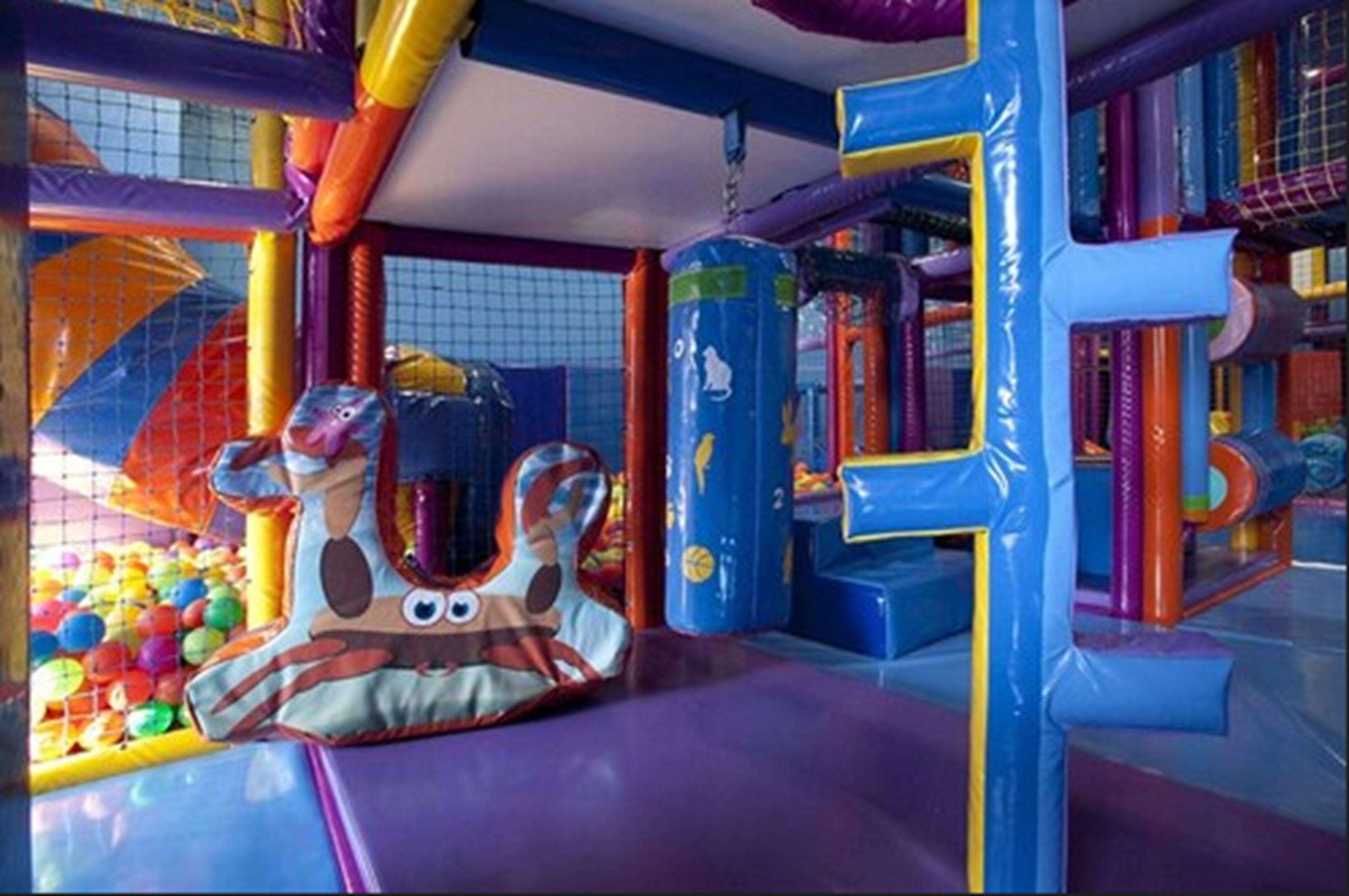 Un área de juegos interior colorida con diversas estructuras de juego y una piscina de pelotas.