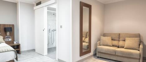 Un dormitorio moderno con una cama, una mesita de noche, un espejo y un sofá.