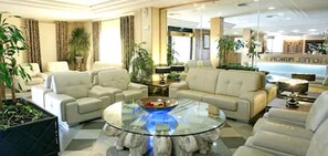 Un salon spacieux avec une table basse en verre, des canapés beige et des plantes en pot.