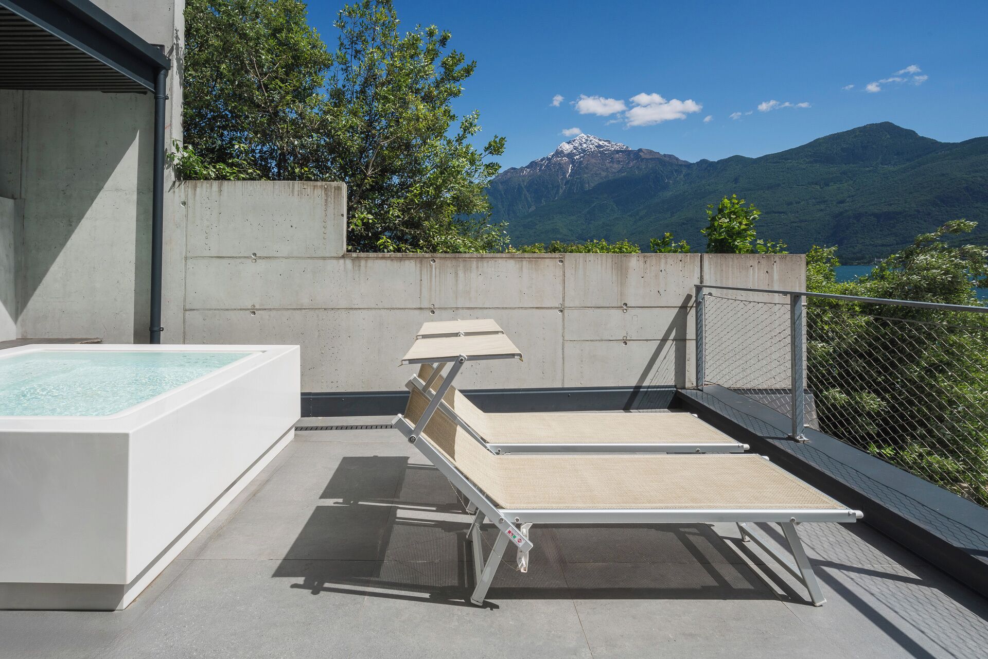 A rooftop terrace with a hot tub, lounge chairs, and a view of mountains.