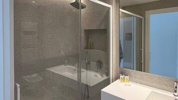Un baño moderno con ducha envuelta en vidrio, un lavabo blanco y un espejo grande.