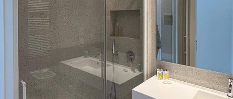 A modern bathroom with a glass-enclosed shower, a white sink, and a large mirror.