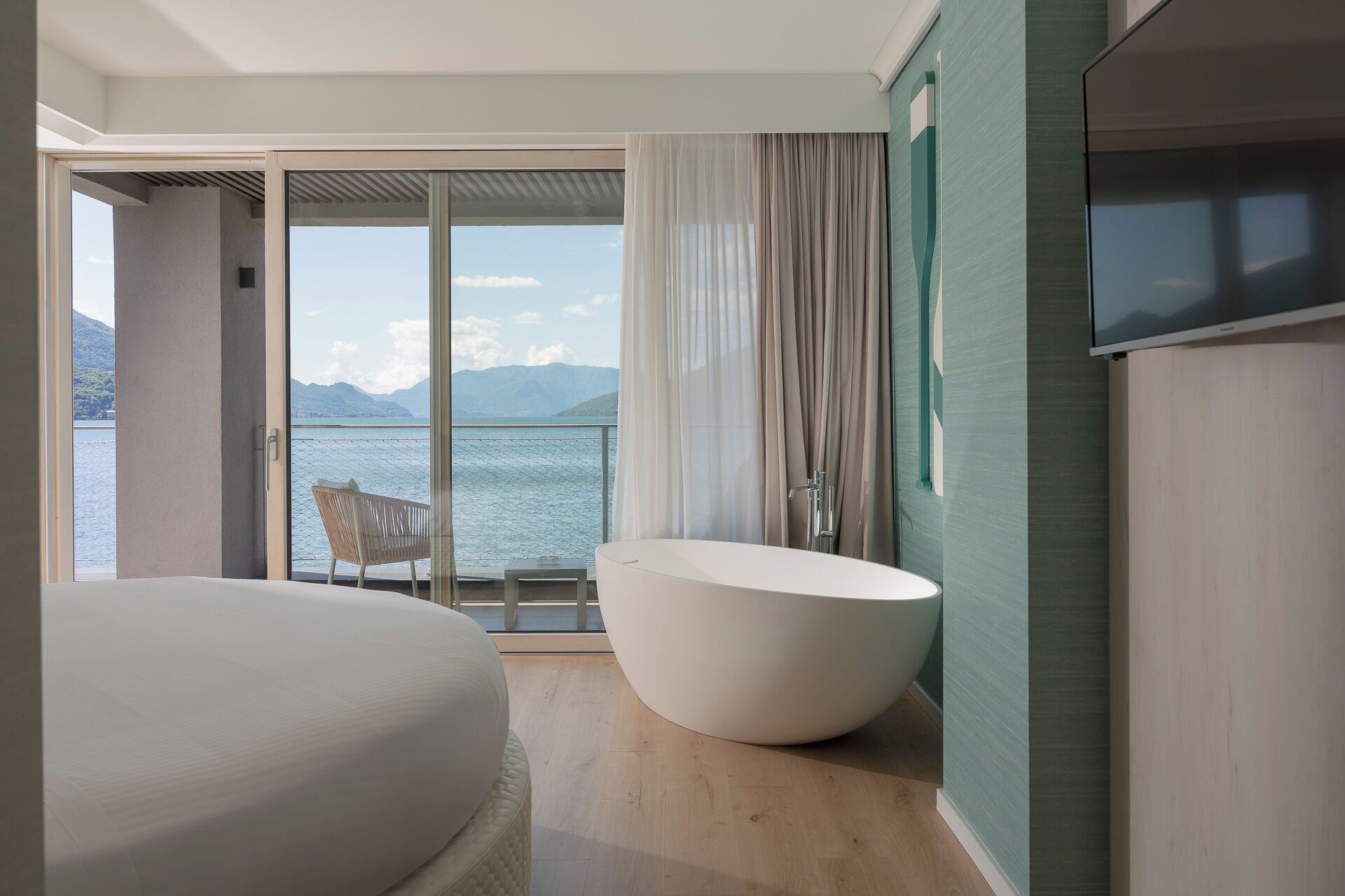 Une salle de bain moderne avec une baignoire sur pieds, un grand lit et une vue sur la mer.