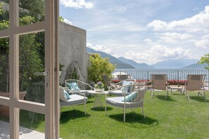 Una terraza con asientos al aire libre, vistas a un lago y montañas al fondo.