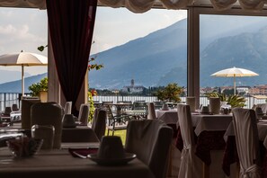 Un restaurante con mesas dispuestas para comer, con vistas a un lago y montañas.