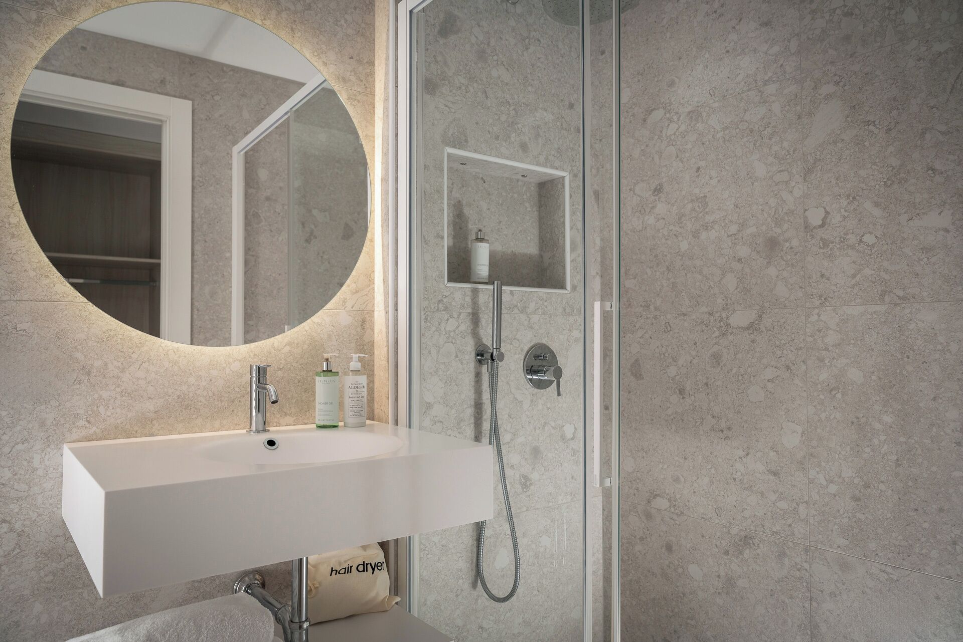 Un baño con lavamanos blanco, un espejo redondo y zona de ducha.