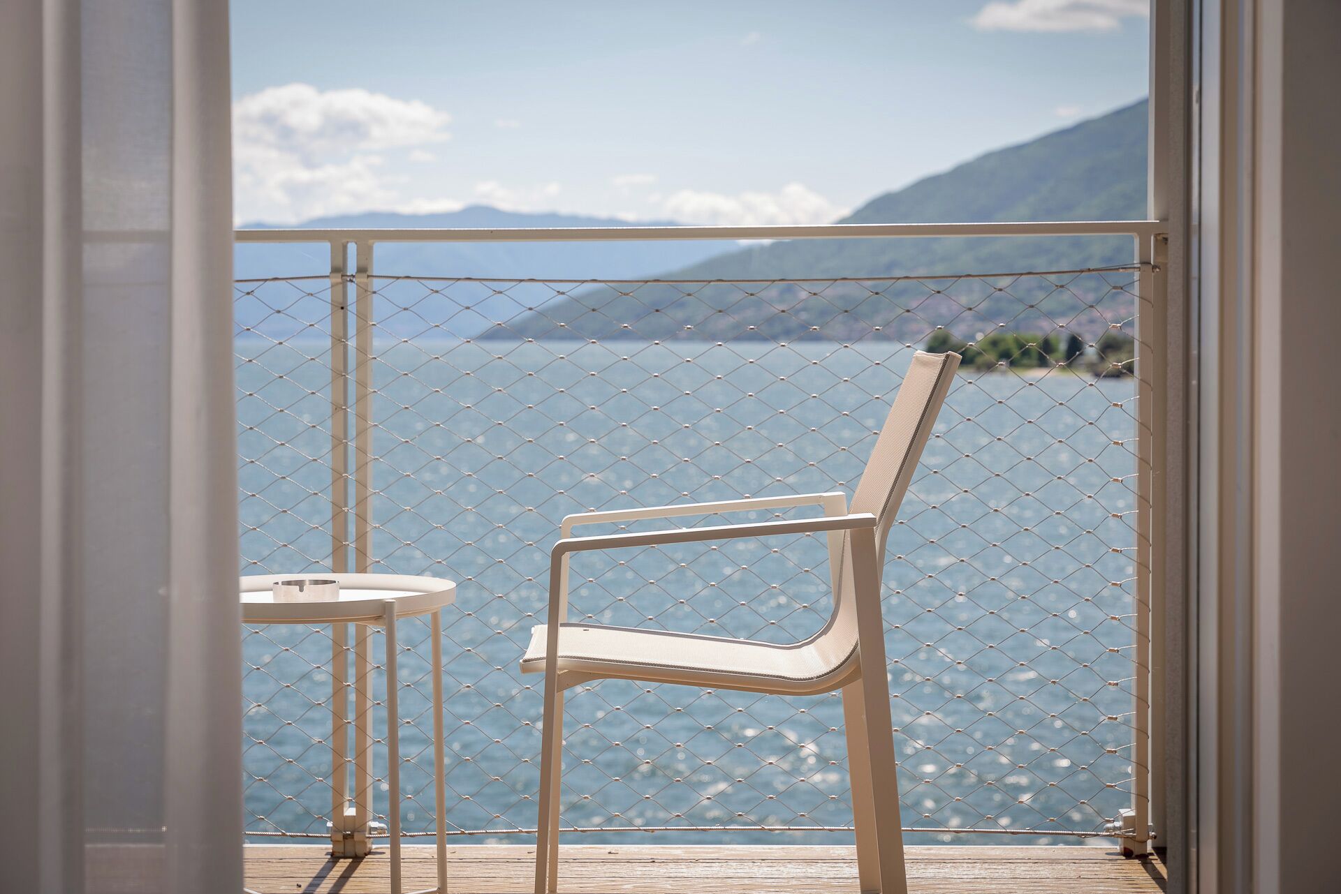 Ein Balkon mit einem Drahtzaun, einem einzelnen Stuhl und einem kleinen runden Tisch.