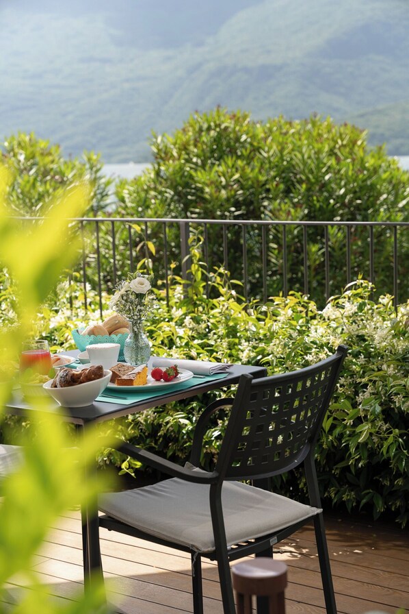 A table set outdoors with a view of lush greenery and mountains in the background. - Hotel Regina (Gravedona)