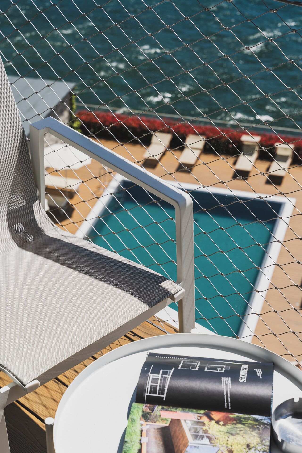 Un espace aménagé au bord de la piscine, avec une chaise et une table, une piscine et une vue sur l’océan.