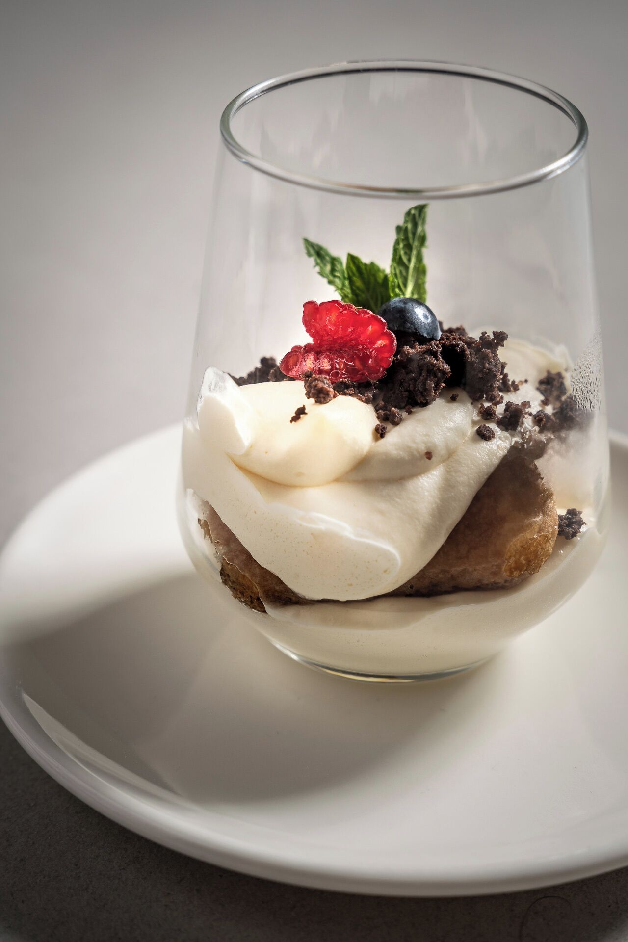 A dessert in a clear glass on a white plate.