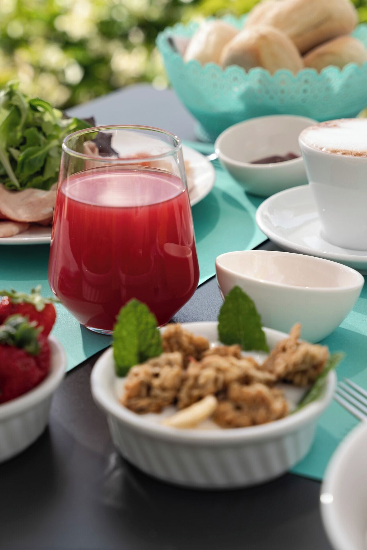 Una mesa servida con un vaso de bebida roja, un bol de nueces y un plato de fresas.
