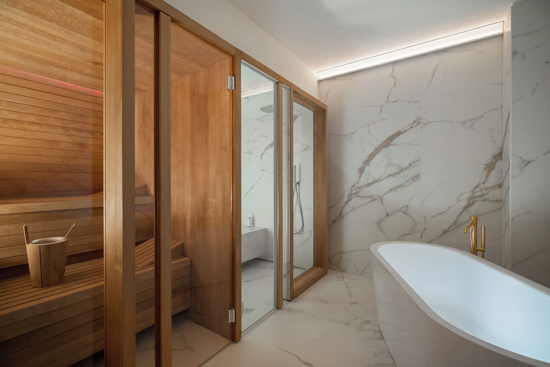 Une salle de bain moderne avec une baignoire sur pieds, des bancs de sauna en bois et des murs en marbre.