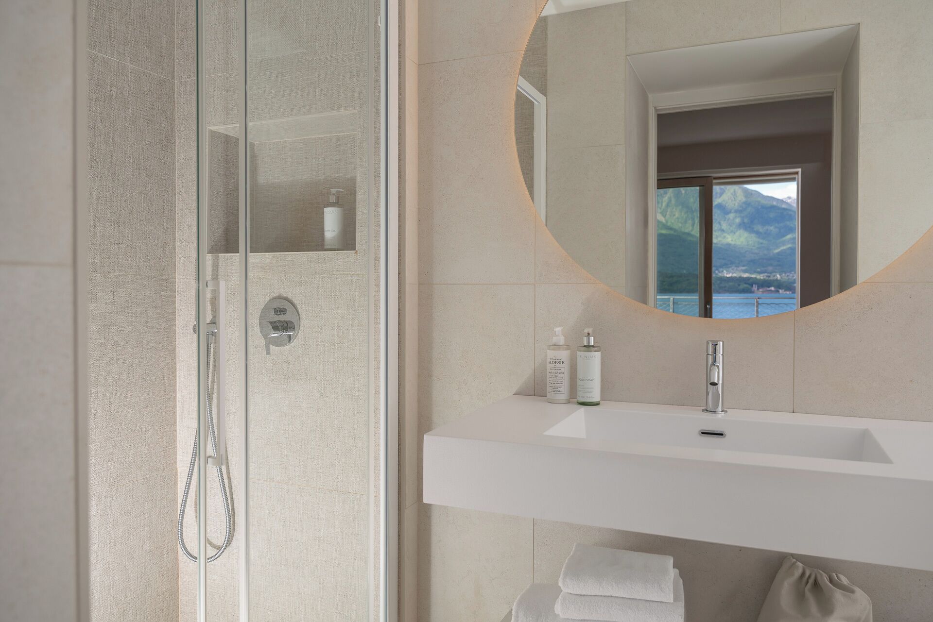 Ein modernes Badezimmer mit einer einteiligen Duschkabine, einem weißen Waschbecken mit Spiegel darüber und Toilettenartikeln auf dem Waschbecken.