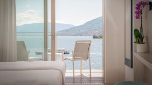 Een hotelkamer met een balkon met uitzicht op een meer en bergen.