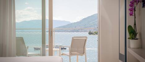 Habitación de hotel con balcón y vistas a un lago y montañas.
