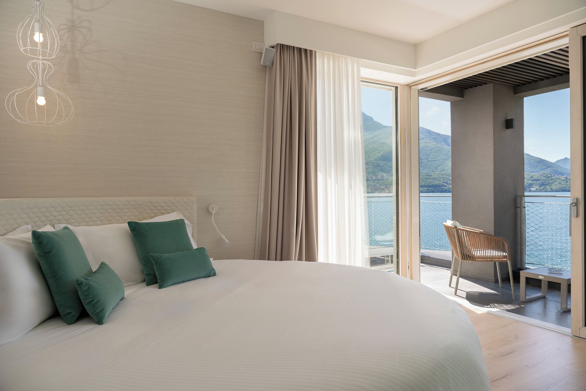 Un dormitorio con una cama grande, vista al lago y un balcón con una silla.