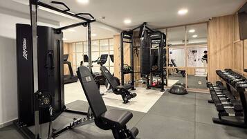 A gym with weightlifting equipment, treadmills, and a mirrored wall.