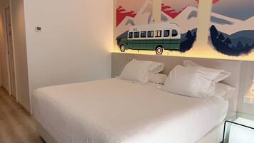Une chambre moderne avec un grand lit, une tête de lit dotée d’un éclairage intégré et une œuvre d’art représentant un train, accrochée au mur.