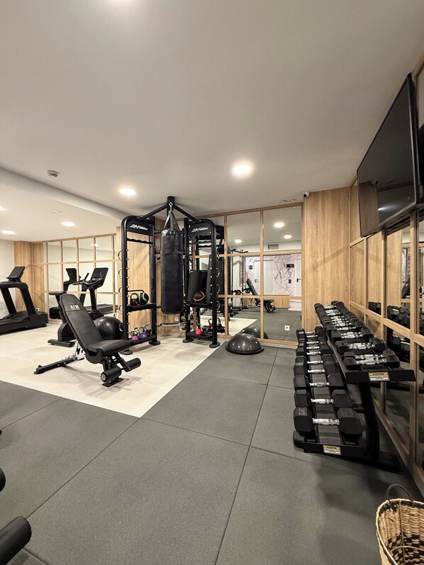 A gym with exercise equipment, treadmills, and dumbbells.