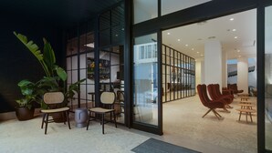 Un intérieur moderne avec une cloison en verre, un coin salon et des plantes d’intérieur.