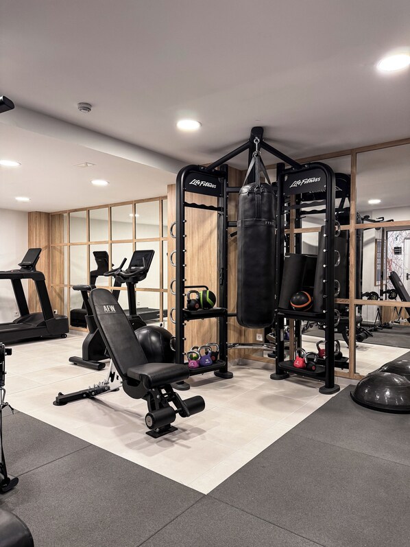 A home gym with a treadmill, weight bench, kettlebells, and a punching bag. - Dormirdcine Alicante (Alicante)