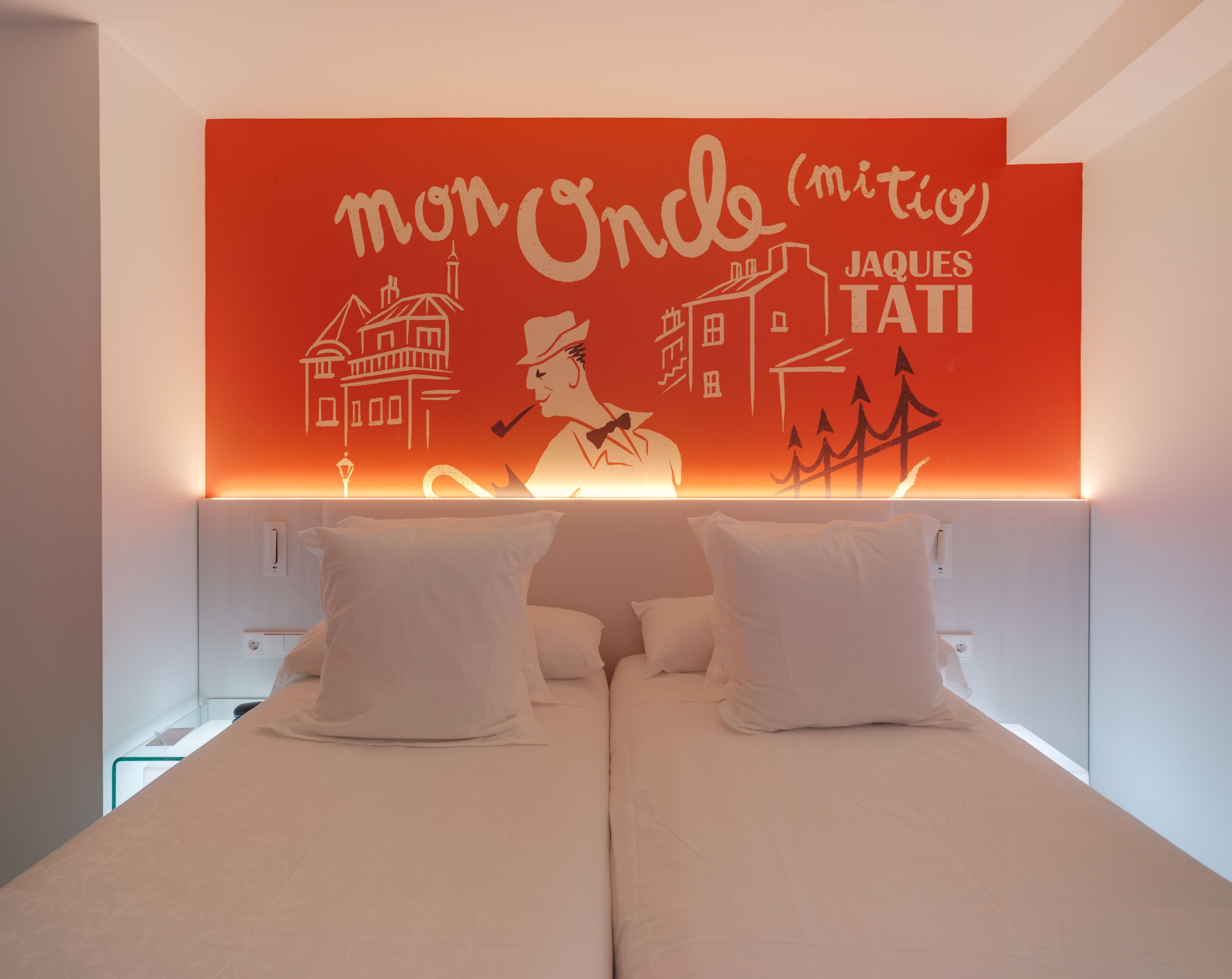 Een hotelkamer met een bed, kussens en een muur met een muurschildering.