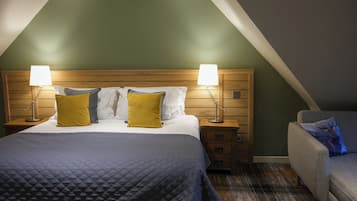 Habitación de hotel con una cama grande, dos mesitas de noche con lámparas, un cabecero de madera y una pared verde decorativa.