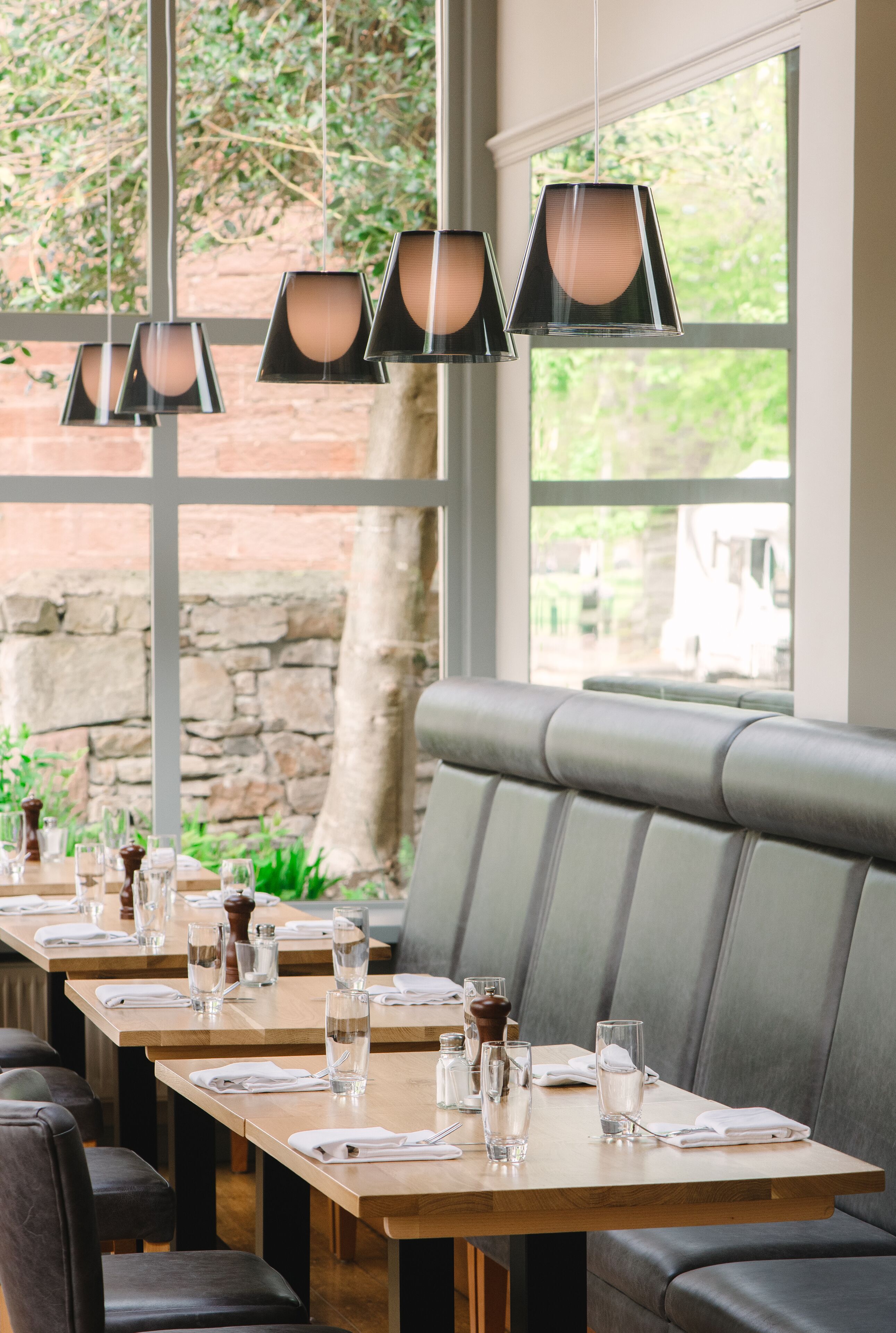 A restaurant with wooden tables and grey cushioned seating.