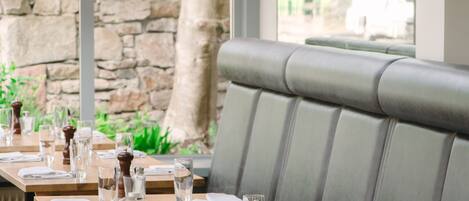 A restaurant with wooden tables and grey cushioned seating.