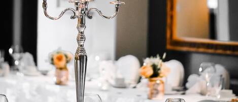Una mesa de comedor formal con candelabro, mantel blanco y cristalería vacía.