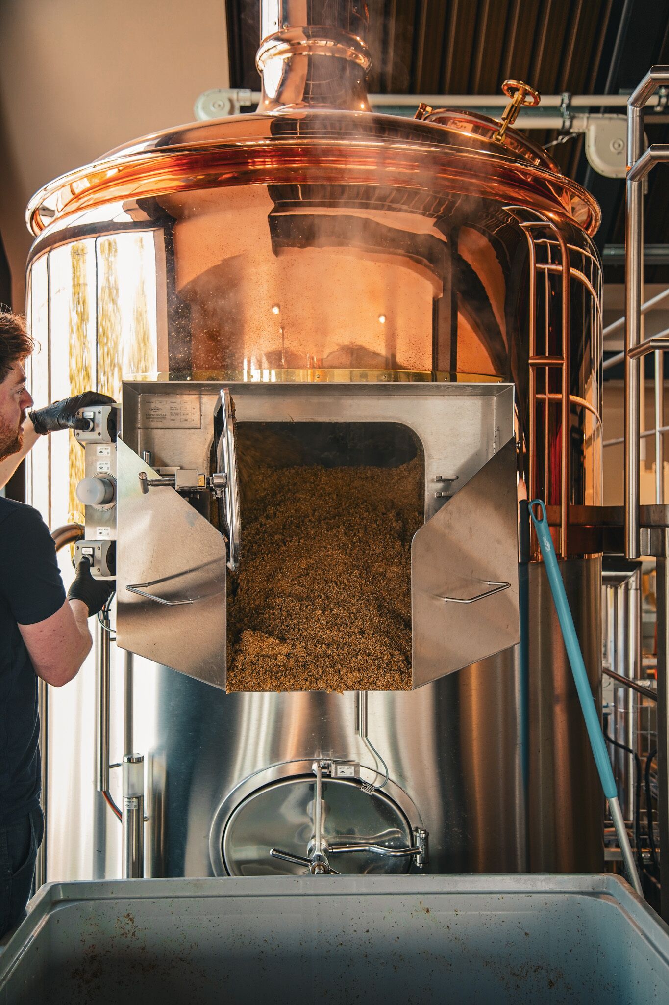 A large industrial brewing apparatus with a transparent lid, a spigot, and a metal funnel.