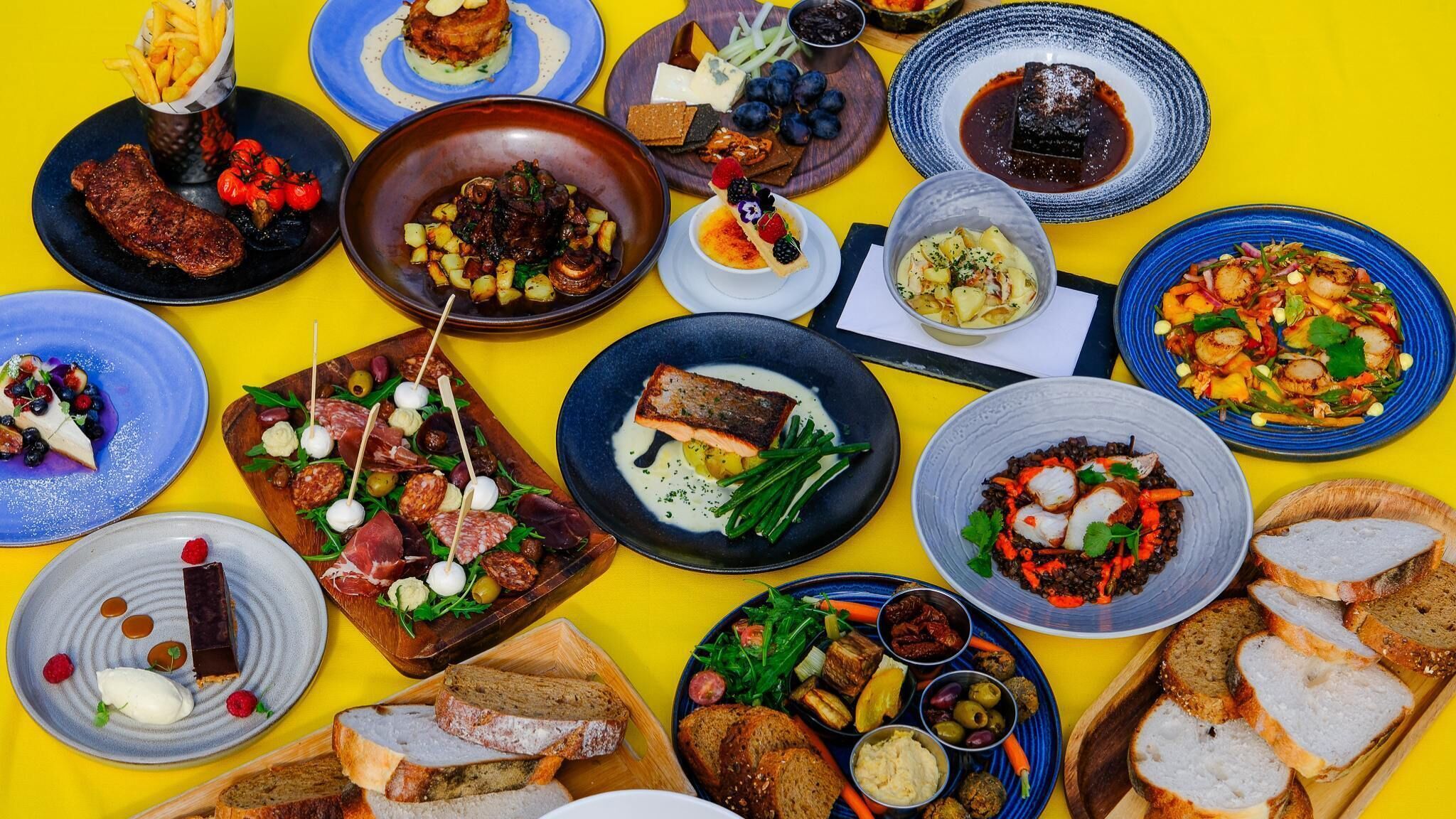 A variety of dishes and bread on a yellow table.